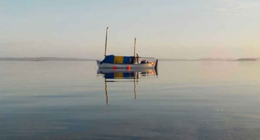 a sailboat rests in still water on an outward bound expedition in maine